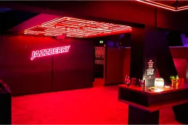 Bar mit neonroter Beleuchtung, moderner Einrichtung und leuchtendem Schriftzug an der Wand.