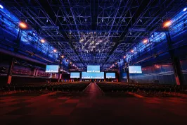 Große Halle, blau beleuchtet mit mehreren beleuchteten Displays, welche von der Decke hängen.