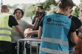 Sicherheitskräfte mit Warnwesten stehen vor einer Absperrung im Freien.