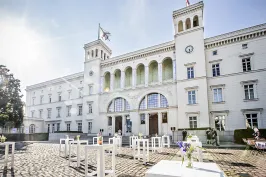 Helles Schlossgebäude mit Türmen, Sonnenschein und weißen Tischen im Innenhof