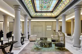 Elegante Hotellobby mit Marmorsäulen und buntem Glasdachfenster