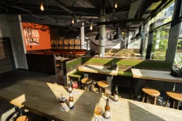 Modernes, sonnendurchflutetes Restaurant mit Holztischen, Flaschen und Gläsern.