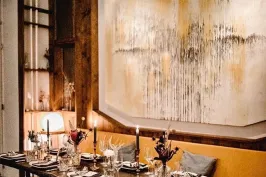 Elegant gedeckter Esstisch mit Kerzen, Bild mit abstrakter Kunst an der Wand.