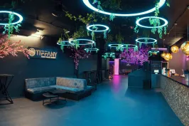 Modern eingerichtete Bar mit Neonlichtern, Pflanzen und gemütlichen Sitzbereichen.