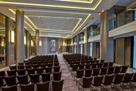 Großer, moderner Konferenzraum mit vielen leeren Stuhlreihen und eleganter Beleuchtung.