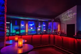 Stimmungsvolle Bar mit buntem Licht, leeren Tischen und Kerzen.