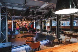 Moderner Veranstaltungsraum mit Bühne, buntem Graffiti und Sitzbereichen.