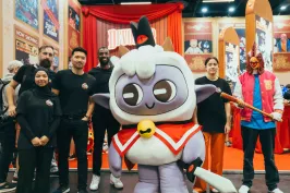 Gruppe von Menschen posiert neben einem großen, bunten Maskottchenkostüm.