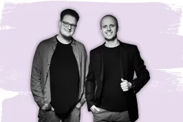 Zwei lächelnde Männer in dunkler Kleidung vor lila Hintergrund, links ein Event DJs Logo.