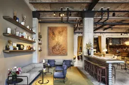 Modernes Hotellobby mit gemütlicher Sitzecke, großen Gemälden und stilvoller Bar.