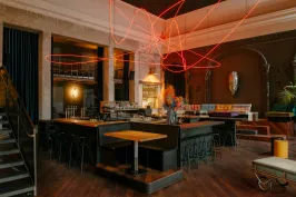 Modernes Restaurant mit Holzboden, bunter Einrichtung und leuchtender roter Lichtinstallation.