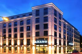 Modern hotel building illuminated at night with "Amano" sign above the entrance.
