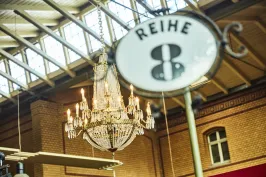 Kronleuchter in einer Halle mit Schild "Reihe 8" im Vordergrund.