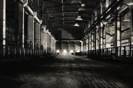 Dunkle, leere Industriehalle mit Licht am Ende des Gebäudes.