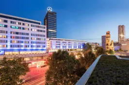 Moderne Stadtansicht bei Dämmerung mit beleuchteten Gebäuden und Hochhäusern.