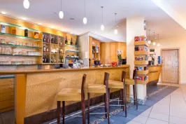 Leere moderne Bar mit Holztheke, Regalen und drei Barhockern.