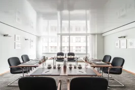 Moderner Konferenzraum mit schwarzem Stuhlkreis und großem Fenster im Hintergrund.