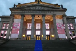 Großes klassisches Gebäude mit Säulen, beleuchtet, blauer Teppich auf der Treppe.