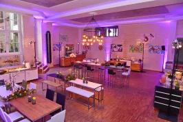 Modern dekorierter Veranstaltungsraum mit lila Beleuchtung und festlich gedeckten Tischen.