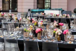 Festlich gedeckte Tische mit Blumen und Gläsern im Freien.