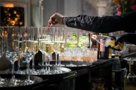 Barkeeper füllt Sekt in Gläser an einer festlich gedeckten Bar.