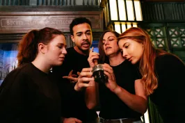 Vier Personen betrachten gemeinsam interessiert ein Glasobjekt.