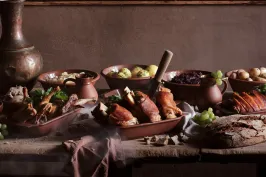 Rustikaler Tisch mit Braten, Kartoffeln, Rotkohl und frischem Brot.