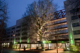 Modern hotel exterior with large lit tree and glass entrance at dusk.