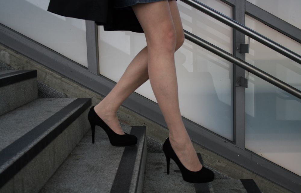 Person wearing black high heels walks down the stairs.