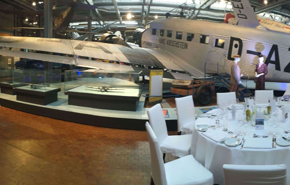 Tische in Bankettbestuhlung im Technikmuseum mit einem alten Austellungsflugzeug im Hintergrund