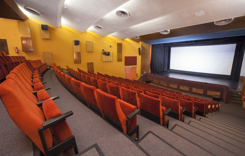 Großer Kinosaal CFB mit orangefarbenden Sitzen und großer Leinwand