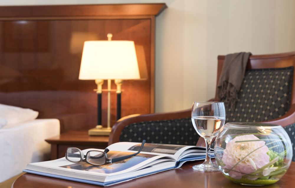 Blick auf Tisch mit aufgeschlagenem Buch und Weinglas im Hotelzimmer Classic