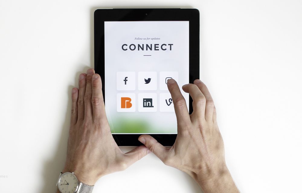 Hände wählen auf einem Tablet unter der Überschrift Connect Social-Media-Buttons aus