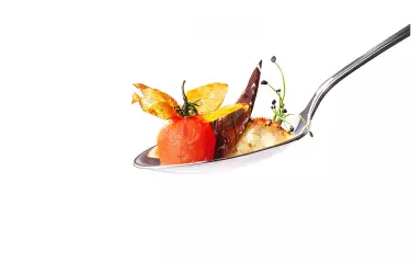 Löffel mit Essen vor weißem Hintergrund
