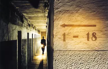 Mensch mit Taschenlampe in einem Bunkergang.