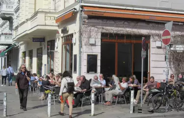 Besucher eines Straßencafés in Schöneberg genießen die ersten warmen Sonnenstrahlen im Frühling.