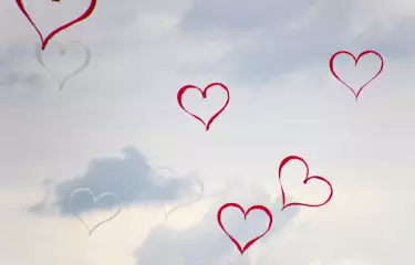 Eine Kunstaktion bildet beim offsite-meeting aufseigende Herzen im Himmel.