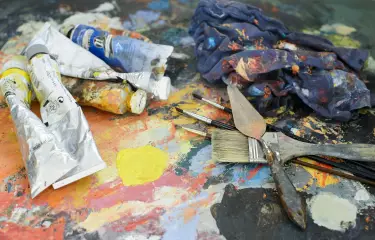 Paint tubes, spatulas and brushes in the studio of a painter