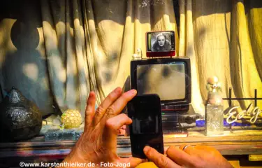 Smartphone-Jagd vor einem kleinen Ladengeschäft mit individueller Schaufenstergestaltung