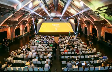 Meeting Guide Berlin satis&fy Gigaset 2015 im WECC Teilnehmer sitzen in Reihenbestuhlung vor einer Bühne