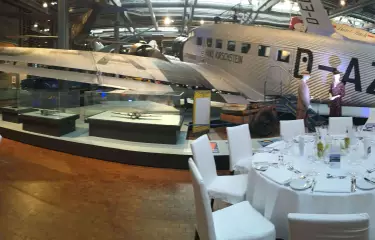 Tische in Bankettbestuhlung im Technikmuseum mit einem alten Austellungsflugzeug im Hintergrund