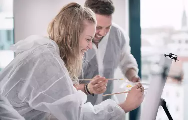 Meeting Guide Berlin Team spirit woman and man painting at an easel