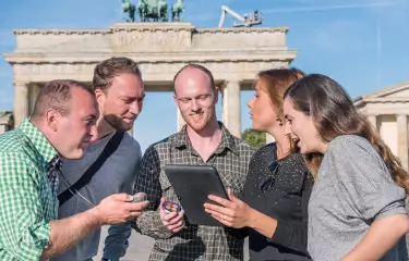 Team mit einem iPad vor dem Brandenburger Tor