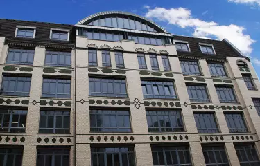 Gekacheltes, 5-stöckiges Gebäude, blauer Himmel mit weißen Wolken