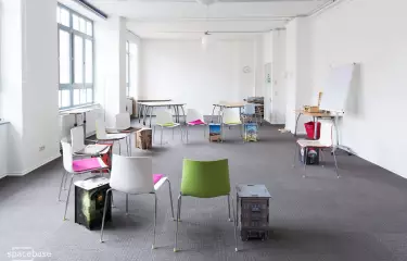 Raum mit grauem Teppich und bunten Stühlen