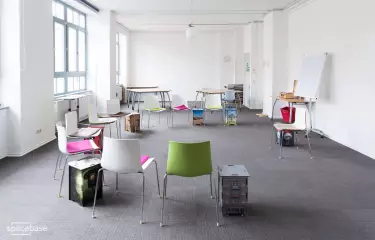 Raum mit grauem Teppich und bunten Stühlen