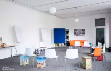 raum mit grauem Teppich, orangenem Sofa, blauer Pinnwand