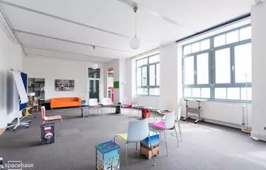 Raum mit grauem Teppich und bunten Stühlen