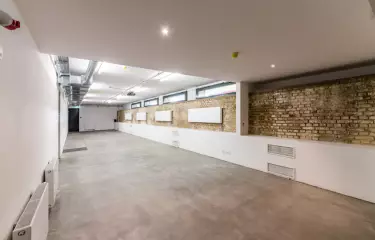 Rustikale Backsteinwände, ein Betonboden, seine schlauchartige Form sowie eine schmale Fensterfront geben dem Lichtkeller im Souterrain des Kachelhauses einen klaren Look. 