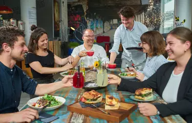 Personen sitzten am Tisch mit Essen und Getränken